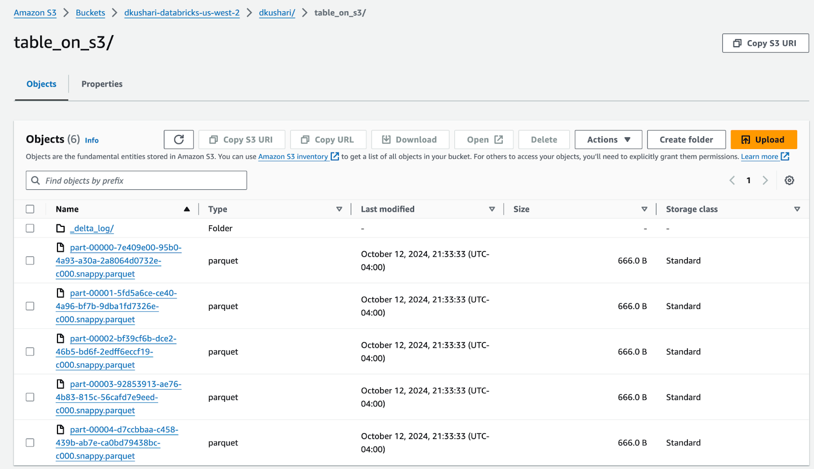 Amazon S3 bucket interface showing the contents of the folder &#x27;table_on_s3&#x27; in the &#x27;dkushari&#x27; bucket. The folder contains a &#x27;_delta_log&#x27; subfolder and several Parquet files with unique names, each approximately 666 bytes in size, last modified on October 12, 2024.